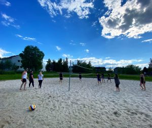 To lag som spiller sandvolleyballkamp mot hverandre i solskinnsvær.
